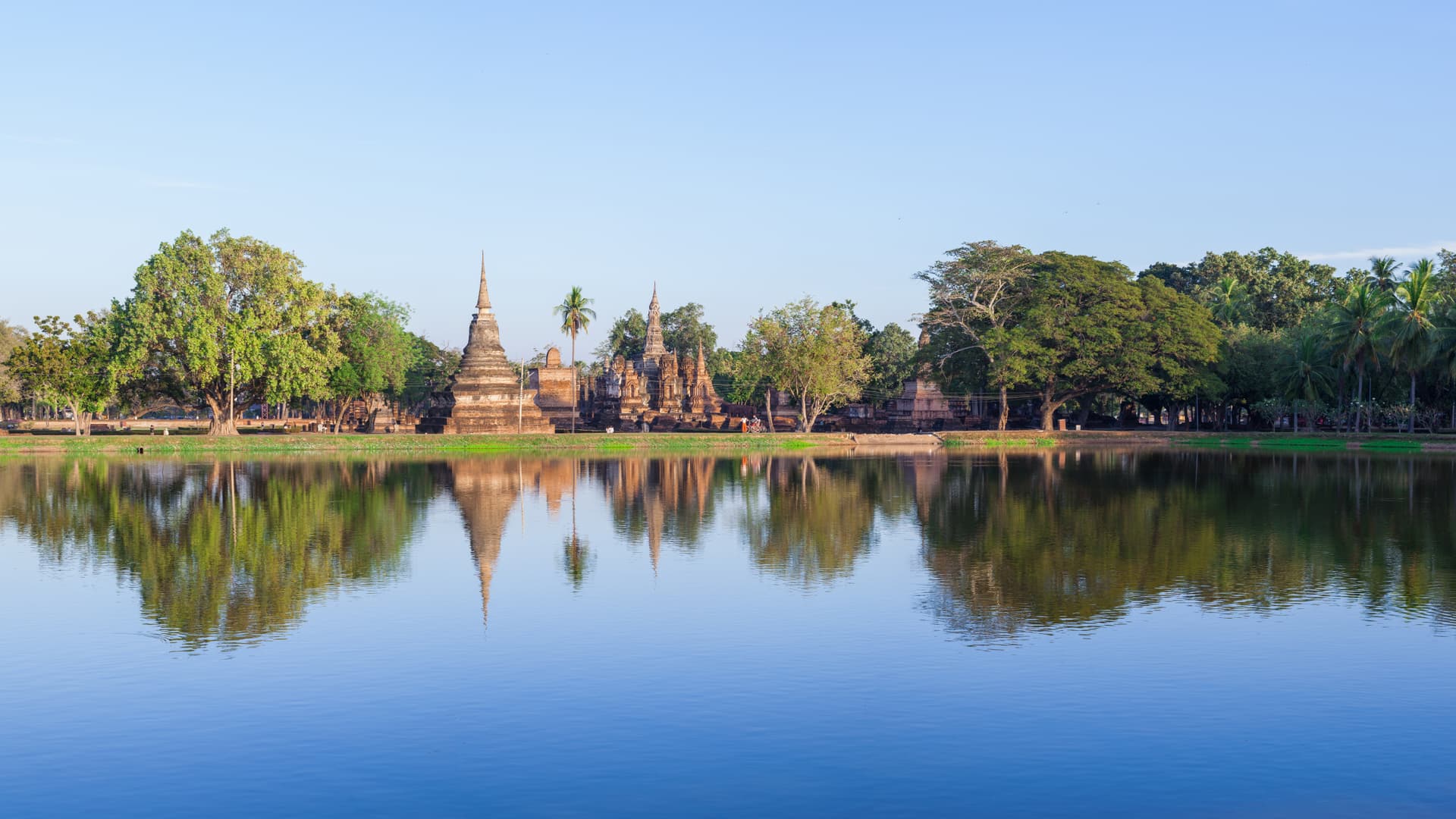 De chedis van Wat Mahathat weerspiegeld in de vijver van het historisch park van Sukhothai