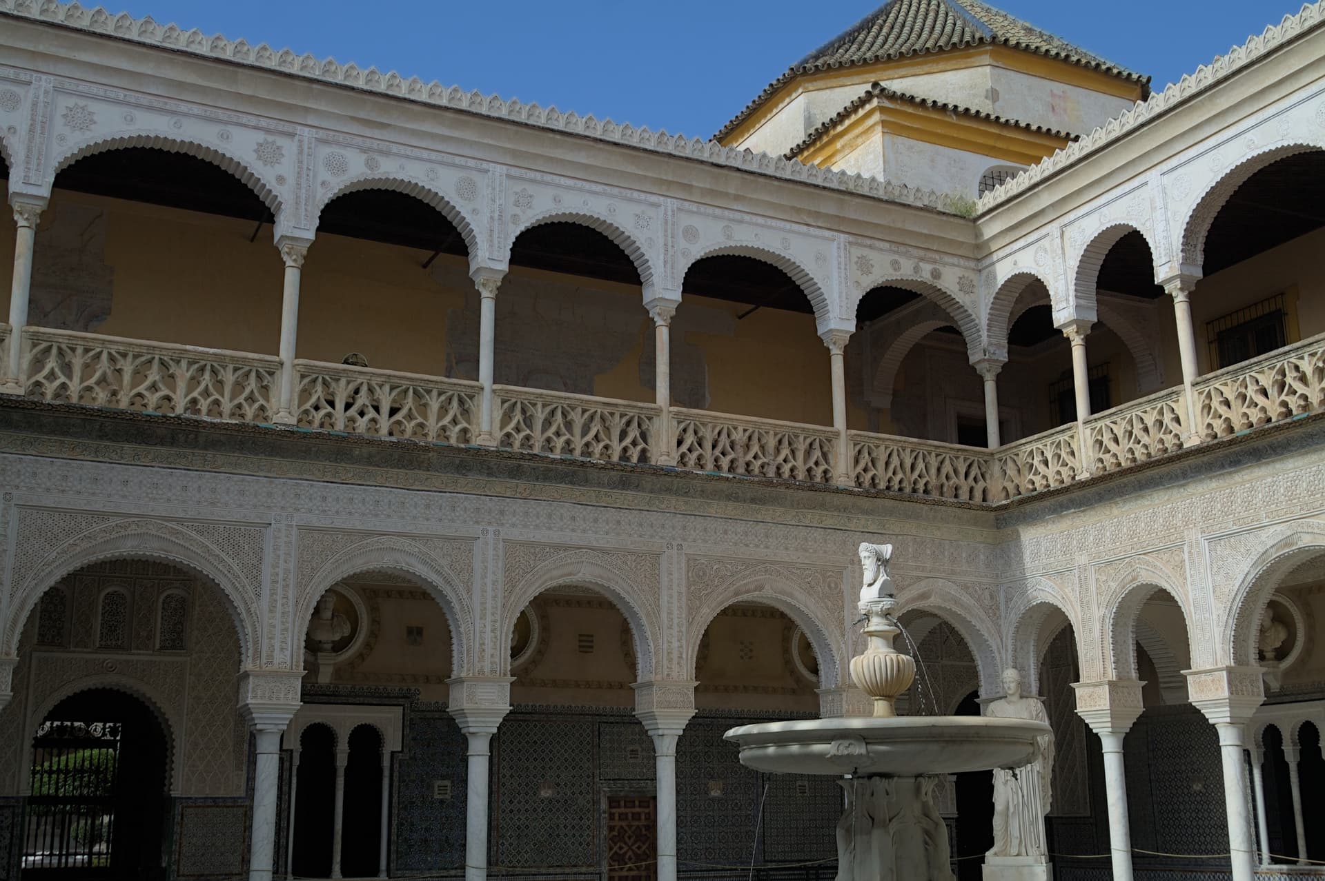 De Mudéjar-binnenplaats van de Casa de Pilatos in Sevilla, met tegels, bogen en een fontein