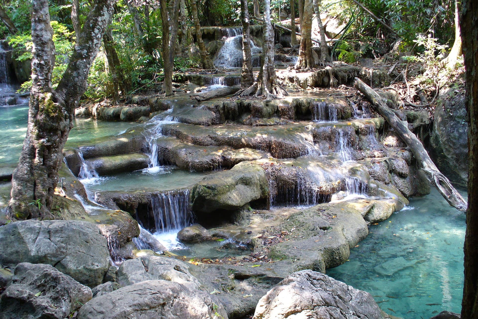 De kalkstenen trappen en helderblauwe bassins van de Erawan-watervallen