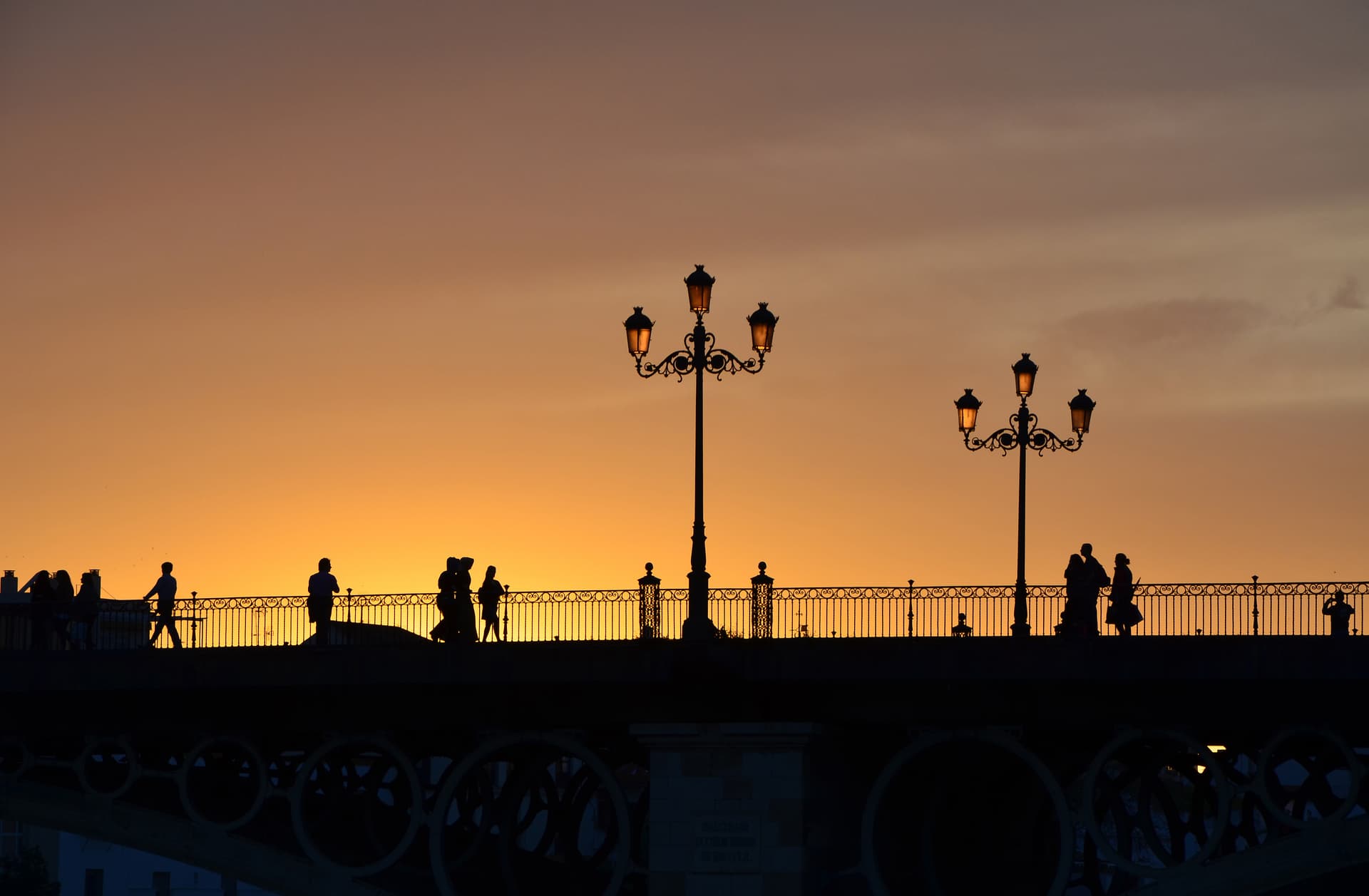 De Puente de Isabel II (Triana-brug) met haar ronde ijzeren bogen, gesilhouetteerd bij zonsondergang in Sevilla