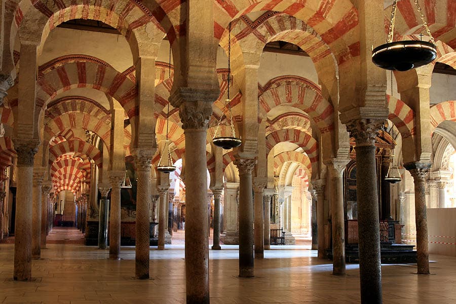 Het interieur van de Mezquita-Catedral van Córdoba — het bos van zuilen met rood-witte dubbele hoefijzerbogen