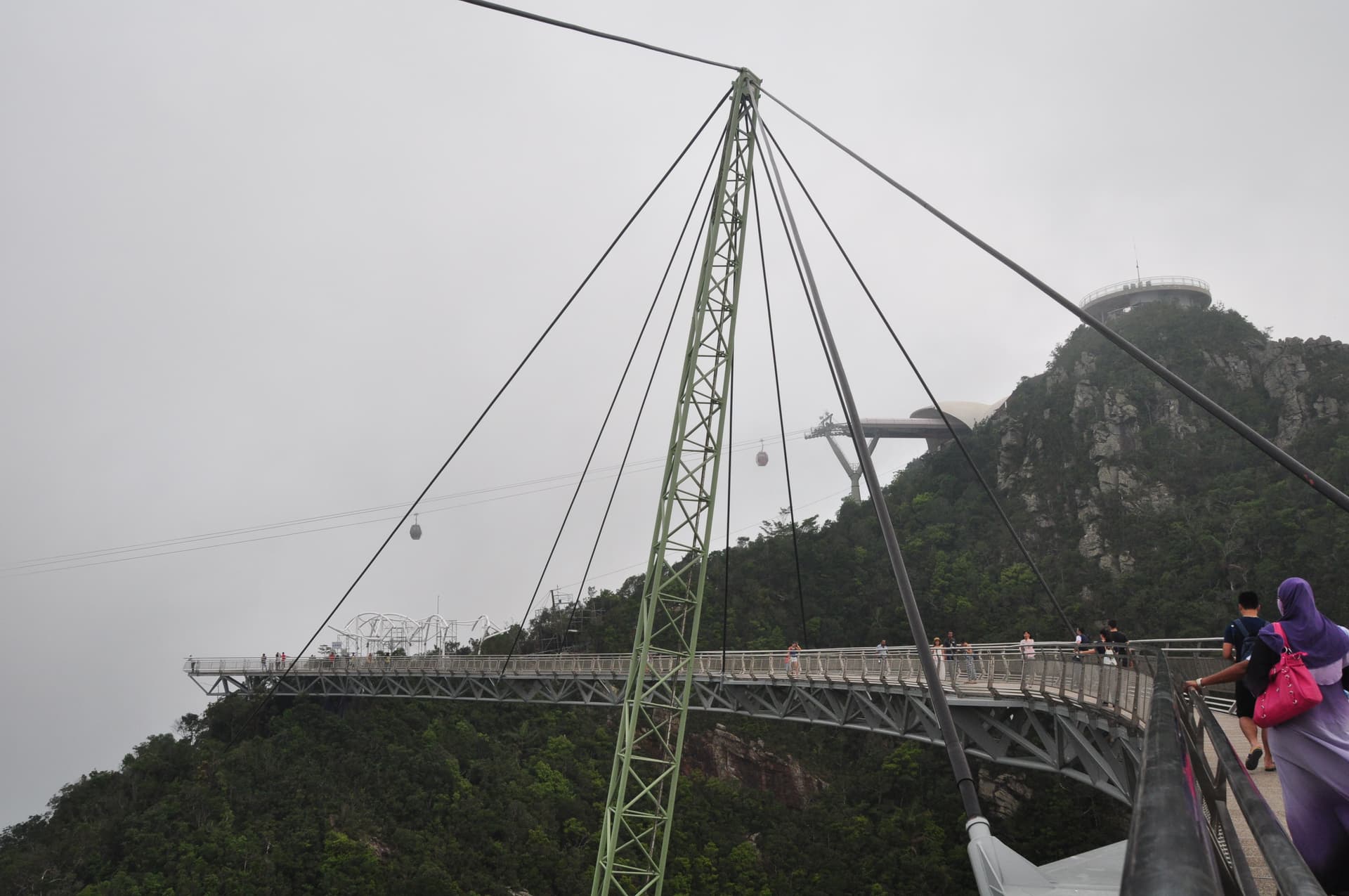 De gebogen voetgangersbrug en kabelbaan van Langkawi boven het beboste bergland