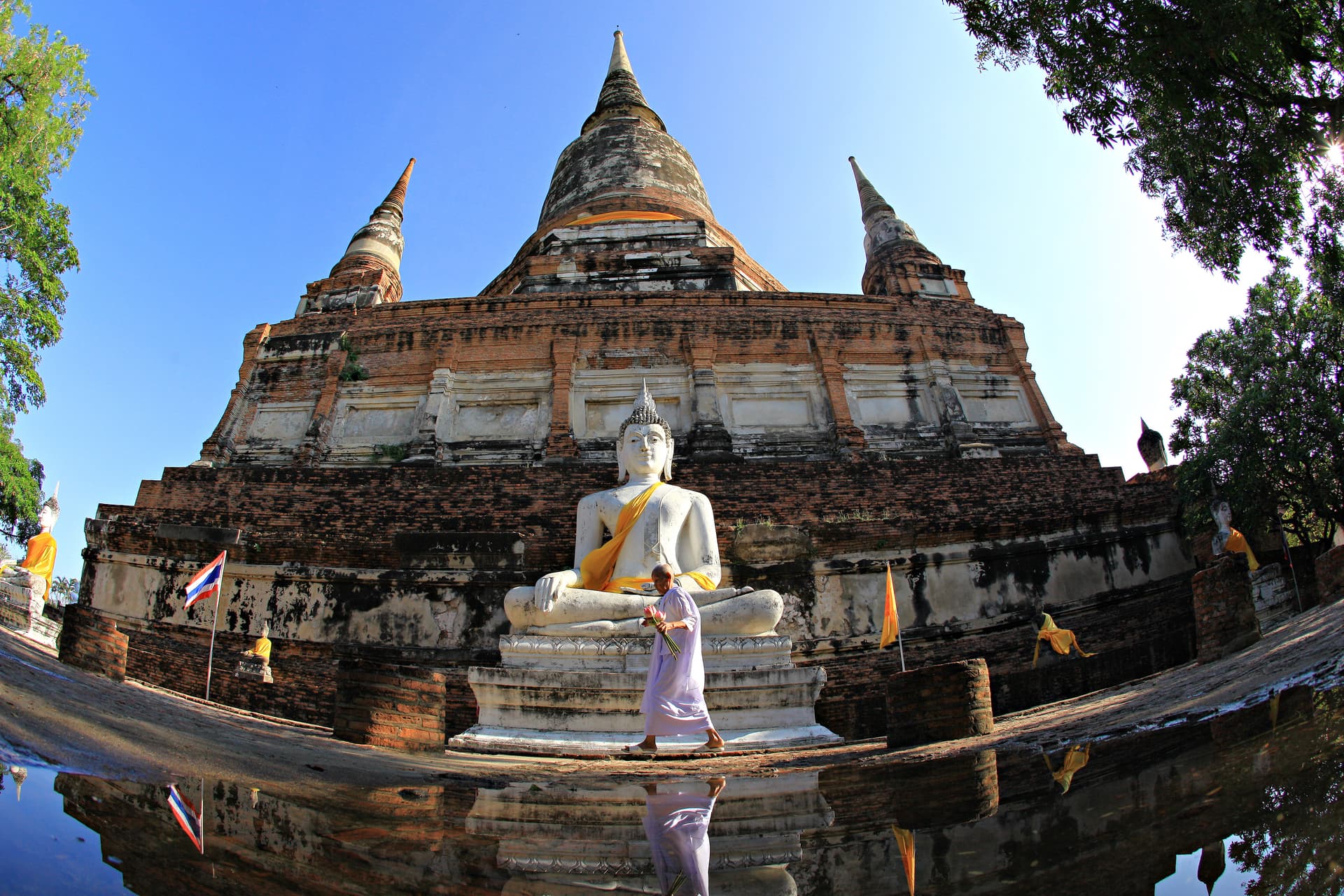 De grote chedi van Wat Yai Chai Mongkhon met een witte boeddha in oranje gewaad ervoor